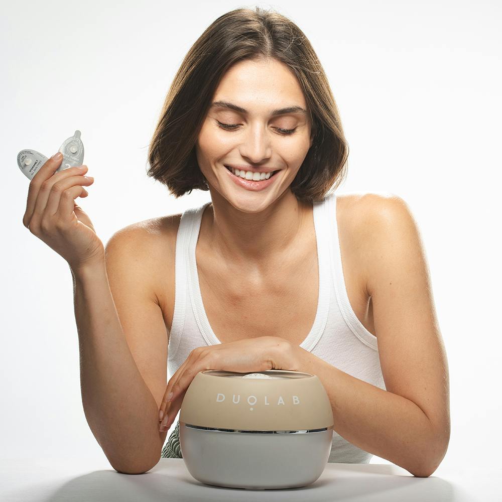 Woman with a Duolab device in front of her holding two capsules